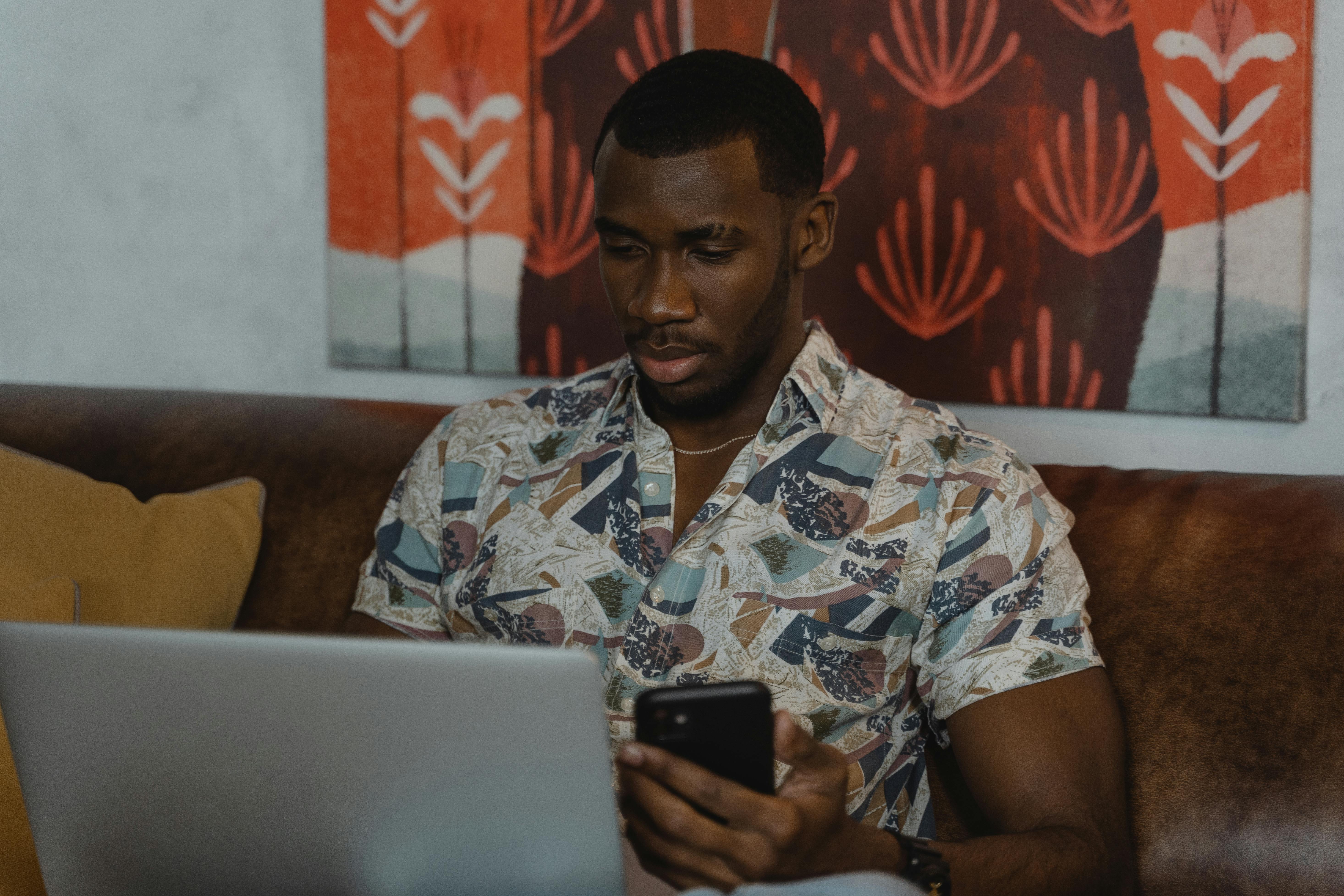 man in white and blue floral button up shirt holding black smartphone