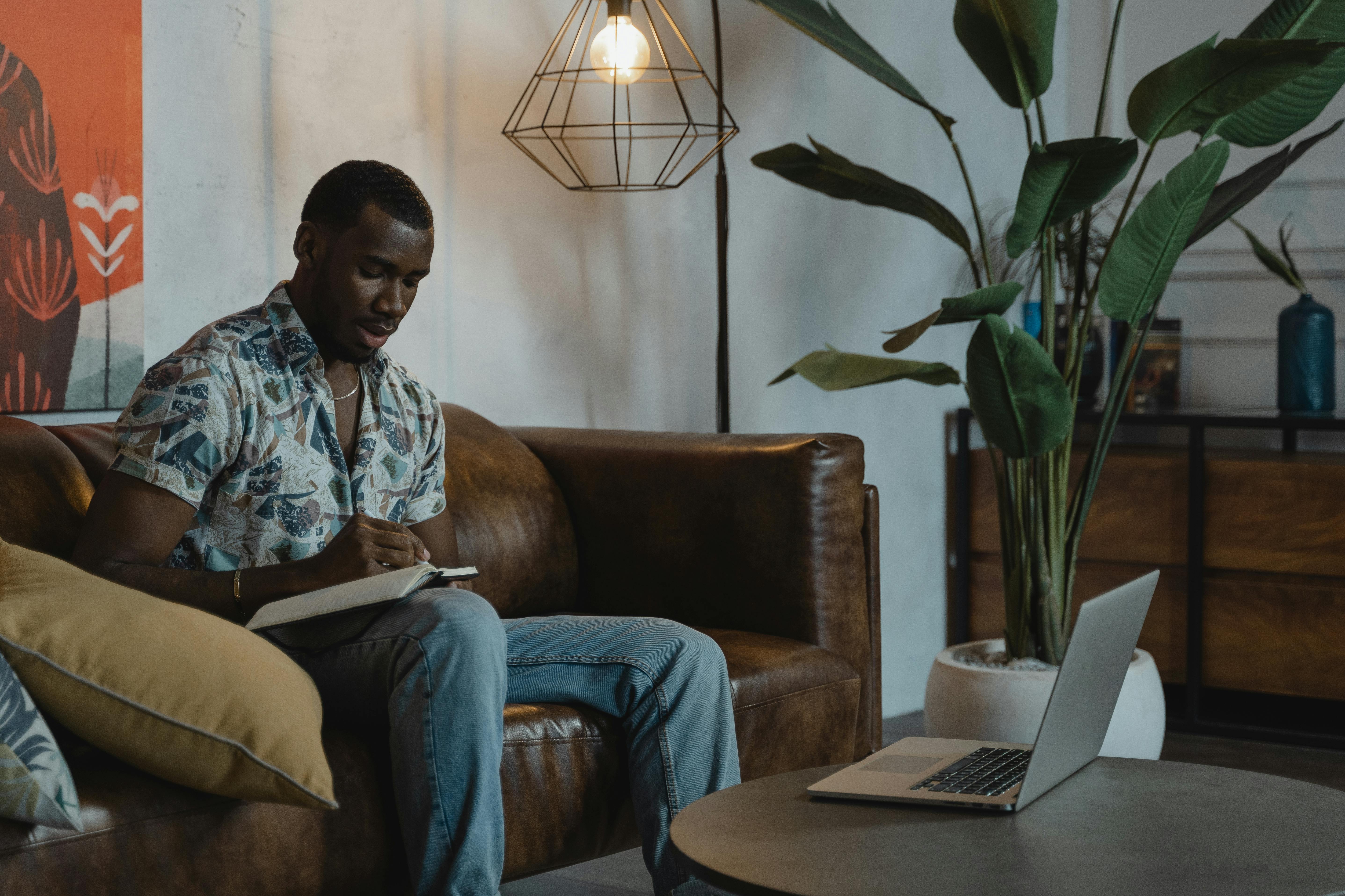 man in blue and white plaid dress shirt sitting on brown couch