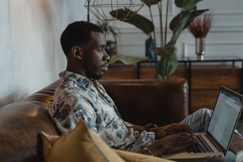 Free A man working on a laptop in a cozy living room setting, illustrating a work from home lifestyle. Stock Photo