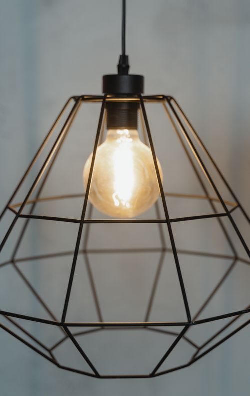 Free Close-up of a modern industrial cage pendant light with an exposed bulb, showcasing minimalist design. Stock Photo