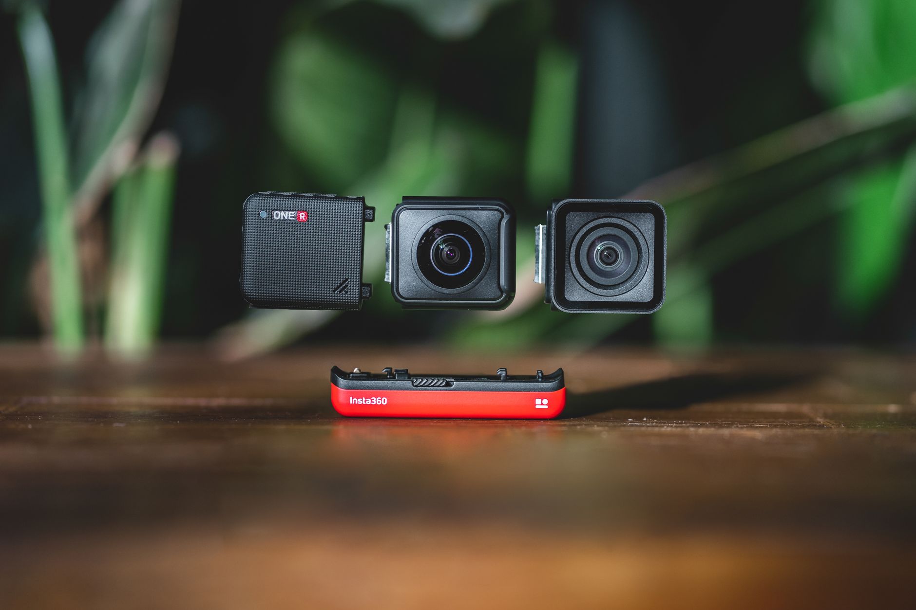 Modular action camera parts floating in focus against a blurred green background.