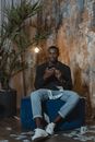 Man in Black Long Sleeve Shirt and Blue Denim Jeans Sitting on Blue Sofa Chair