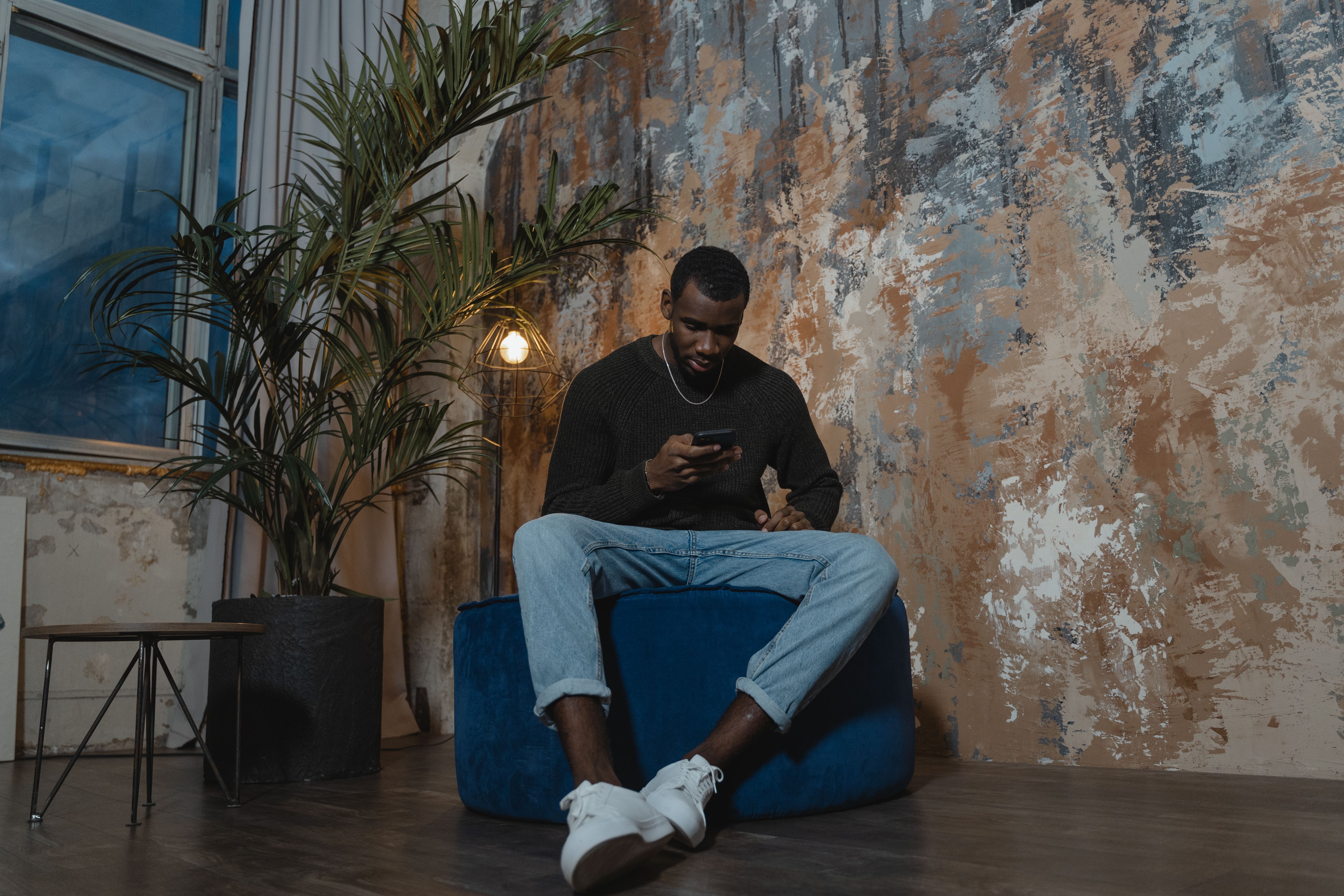 一名男子在时尚的房间里休闲地使用智能手机