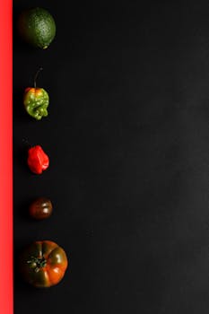A creative flat lay of fresh vegetables and fruits against a bold black background, perfect for health and culinary themes.