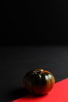 A striking photo of a dark tomato against a contrasting black and red background, showcasing vibrant colors.
