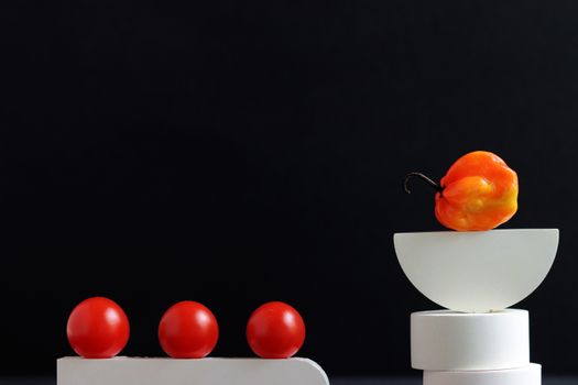 Artistic still life featuring a habanero pepper and cherry tomatoes in a geometric arrangement.