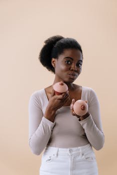 一位妇女手持乳头形状的纸杯蛋糕，面带快乐的表情宣传乳腺癌防治意识