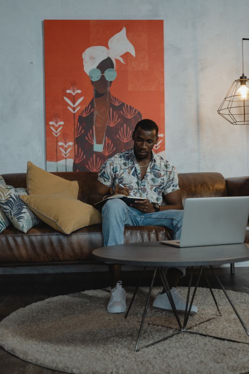 Free Man writing on a tablet in a stylish living room, working from home. Stock Photo