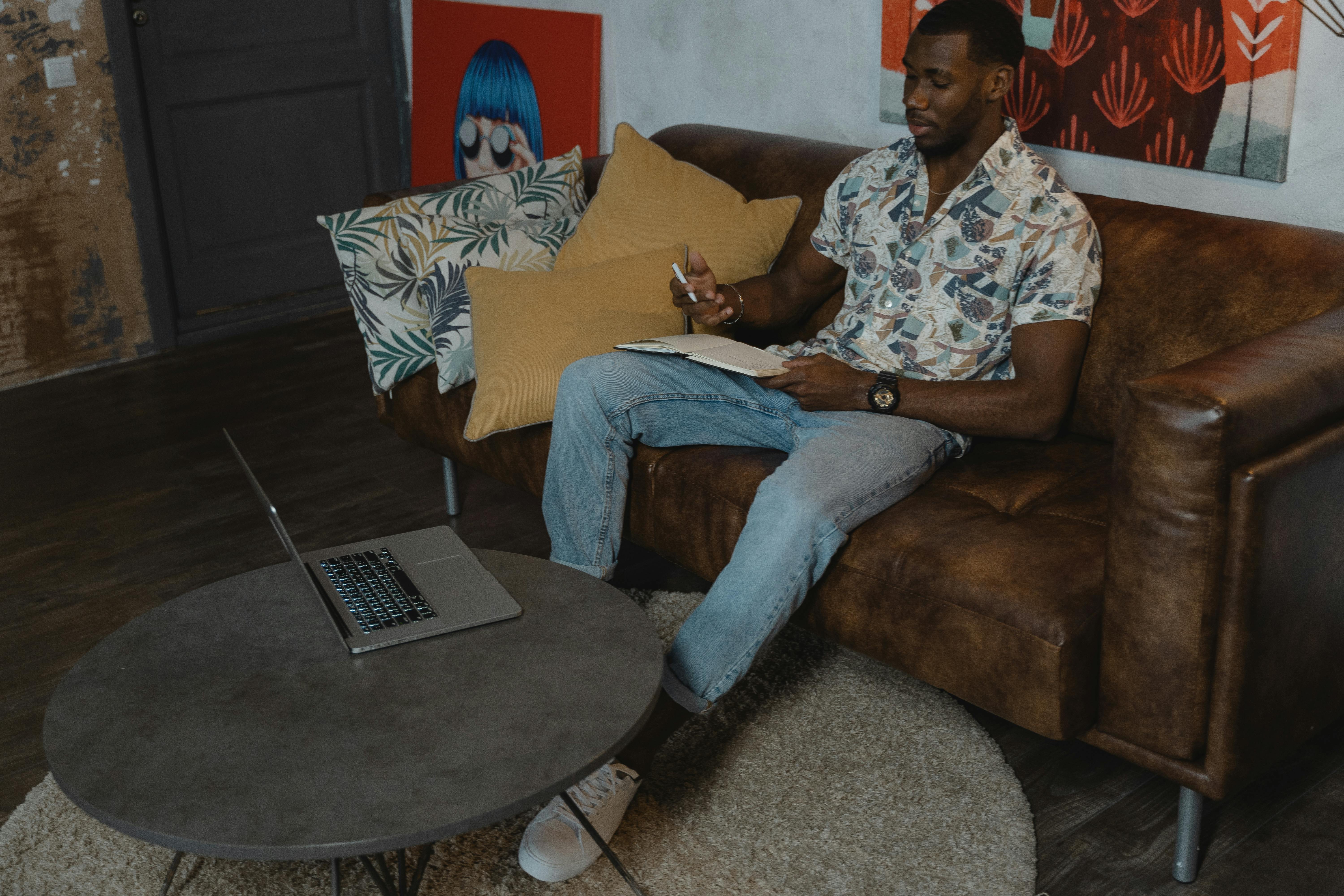 man sitting on brown sofa while having his online class