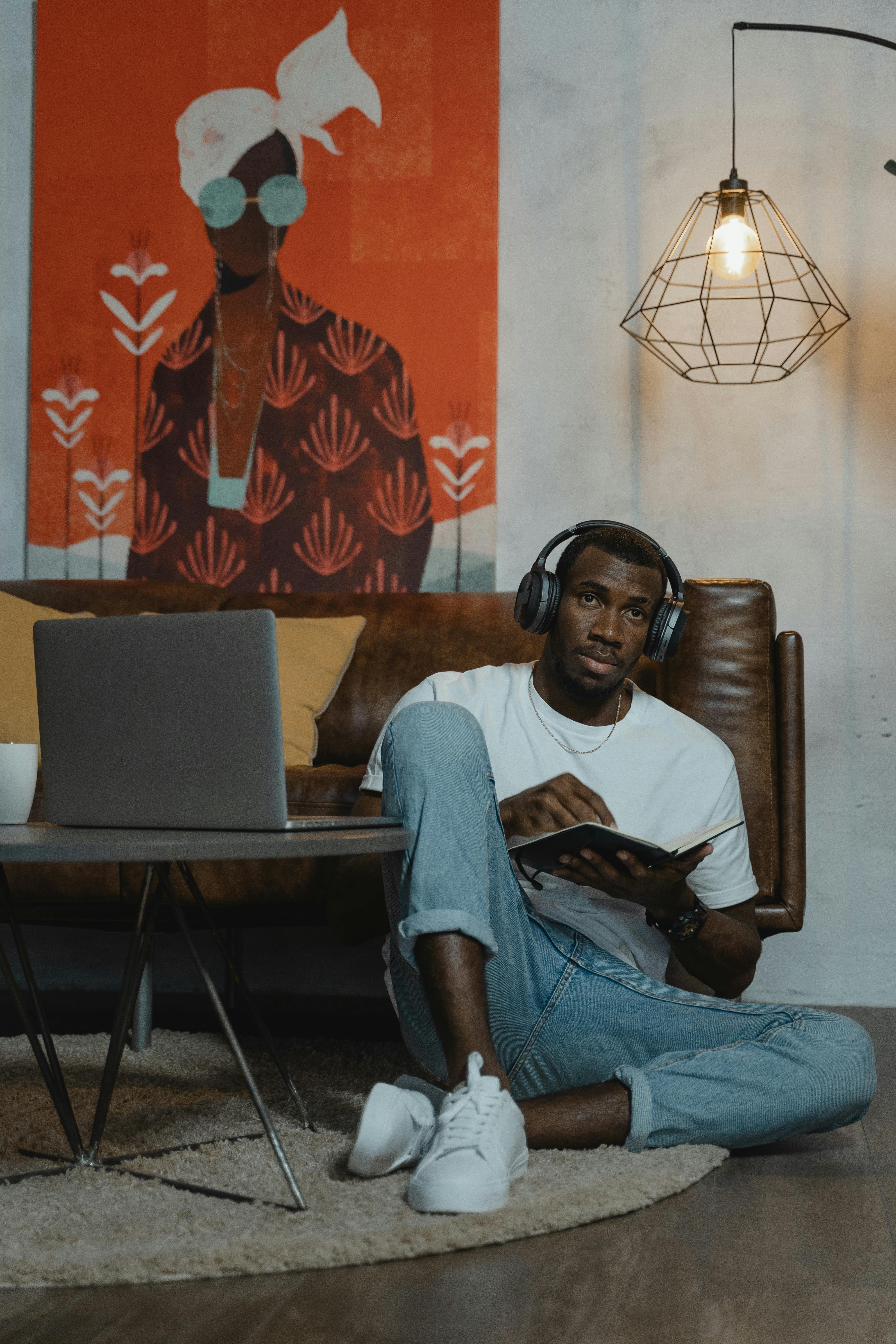 man in white shirt sitting on floor while having his online class