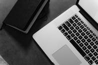 Grayscale Photo of Laptop and Notebook
