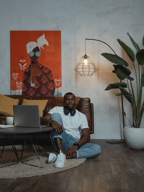 Free African American man engaging in online learning at home, seated in a modern interior. Stock Photo