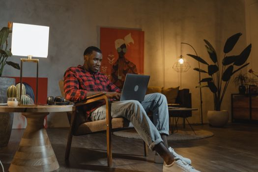 Man working from home on laptop in a stylish and cozy living room setting, embodying modern lifestyle.