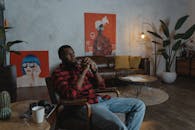 一位穿着格子衬衫的男子坐在装饰现代、充满艺术气息的舒适客厅里，若有所思