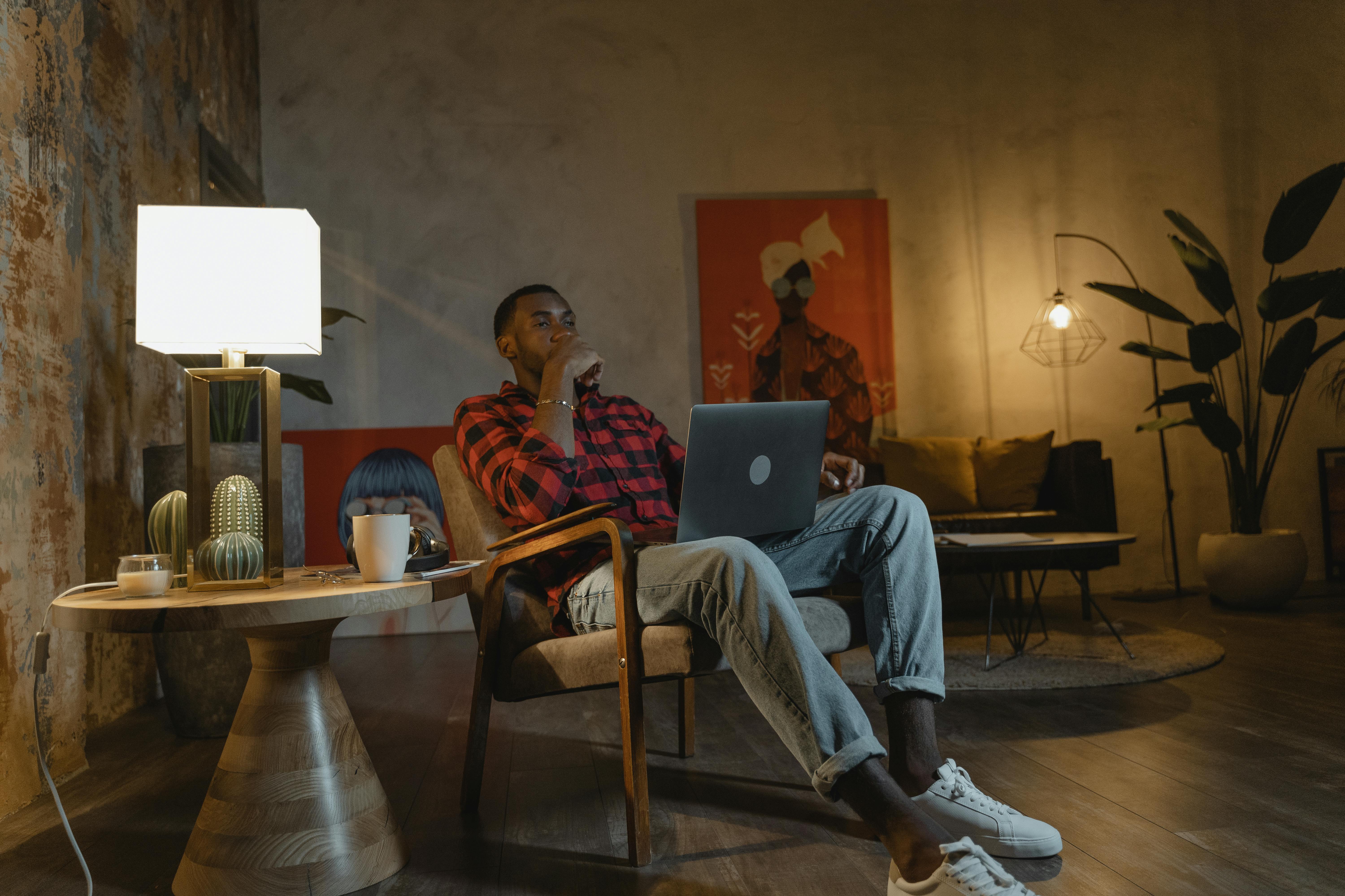 man in red and white stripe polo shirt sitting on brown wooden chair using silver laptop