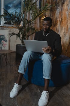 African American man working on laptop in a cozy home setting, focused and engaged.