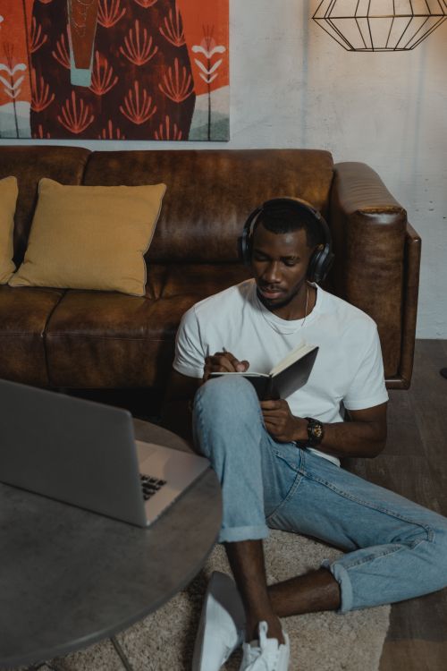 Free African American man studying online with laptop in cozy living room setting. Stock Photo