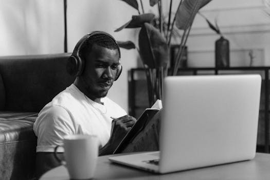 Black and white photo of a man in headphones writing, working remotely from home.
