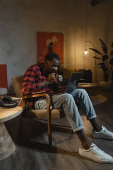 Man in Red and Black Plaid Shirt and Blue Denim Jeans Sitting on Chair Using Laptop