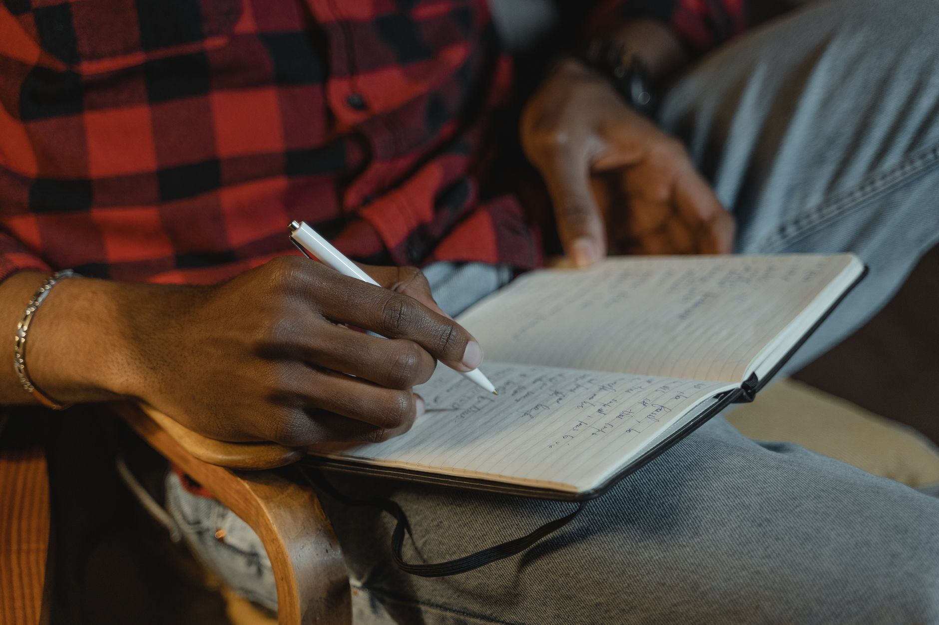 person writing in journal by bedside