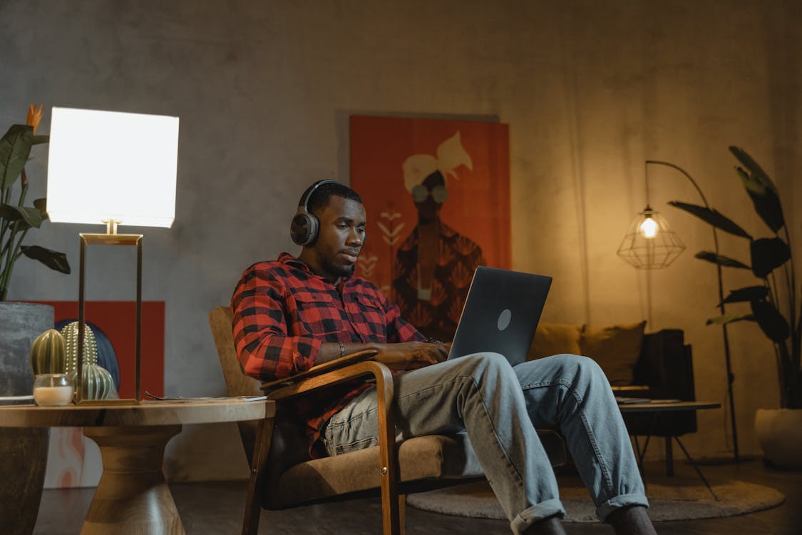 Free  Man Sitting on an Armchair while Using His Laptop Stock Photo