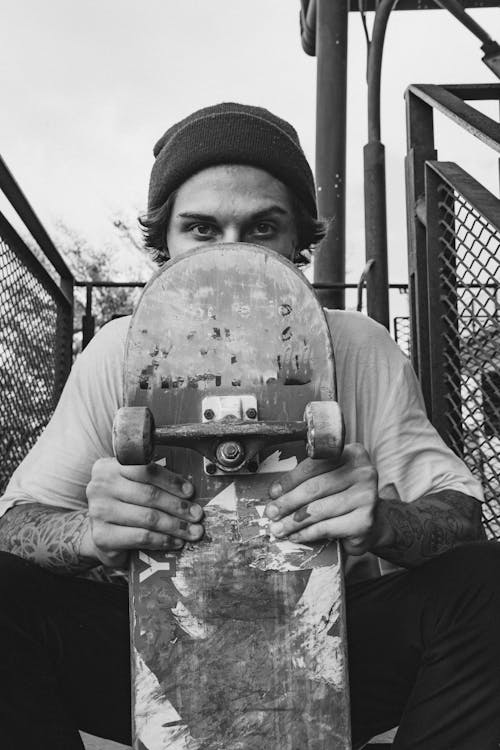 Free Monochrome Photo of Man Holding His Skateboard Close to His Face Stock Photo