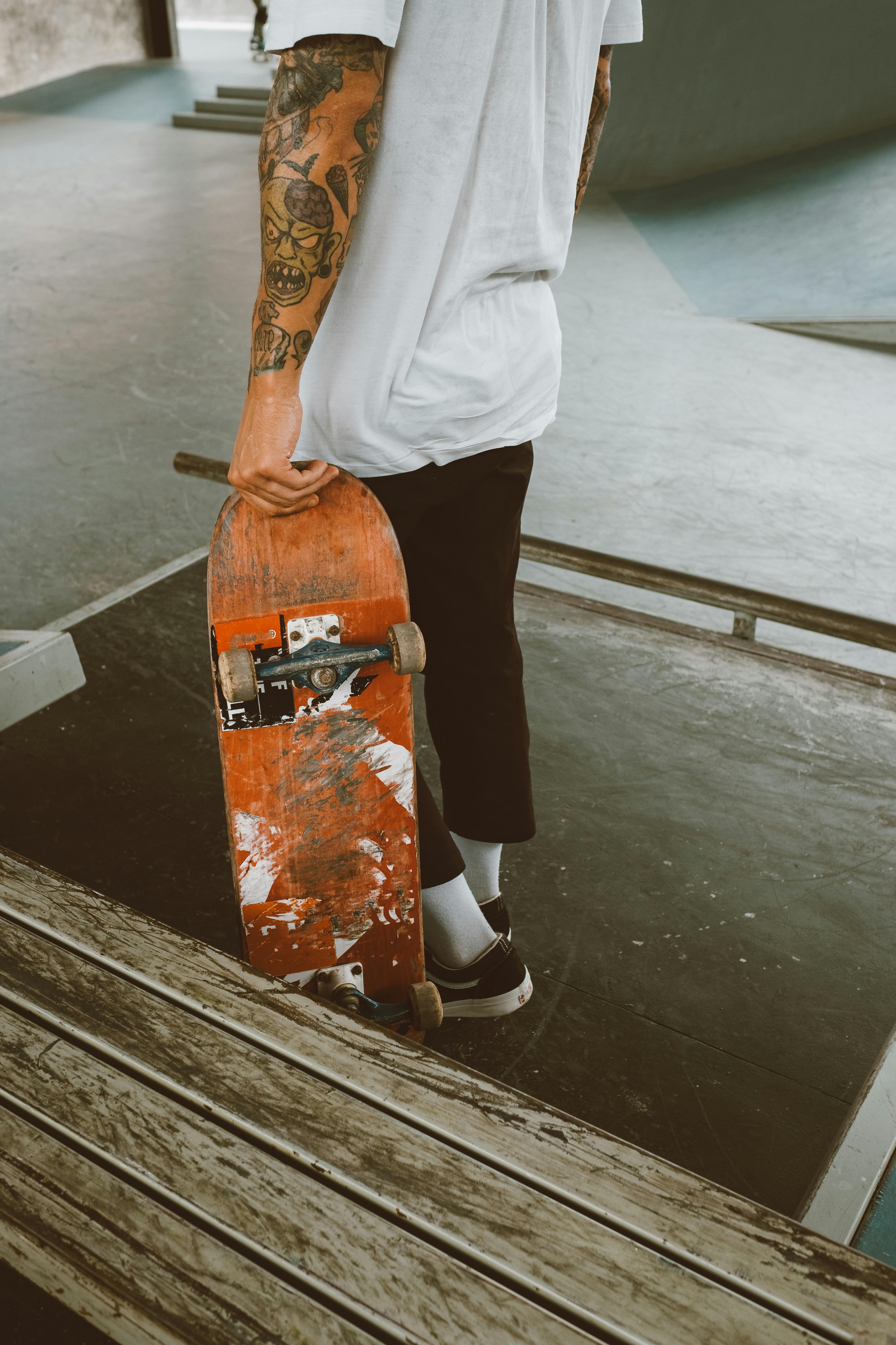 tattooed person holding a skateboard