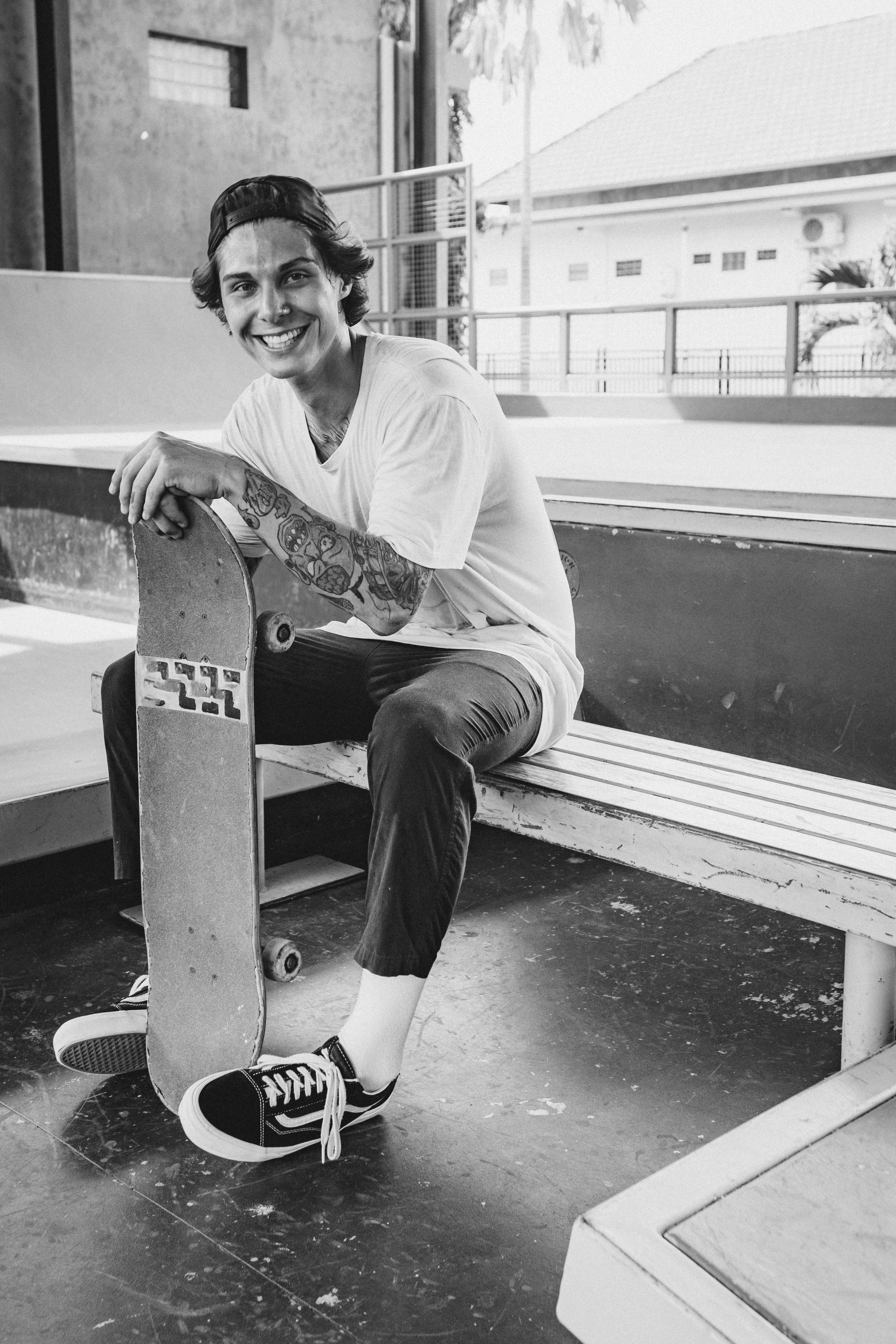 Happy young skateboarder sitting on a bench, smiling outdoors.