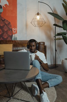 A man working remotely at home, using a laptop while having a coffee in a cozy setting.