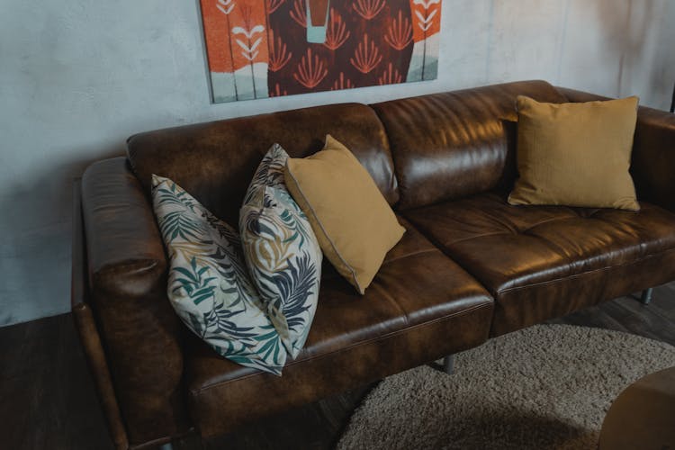 A Brown Leather Couch With Throw Pillows