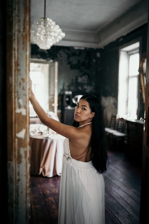 Graceful ethnic woman standing with arm raised in shabby doorway