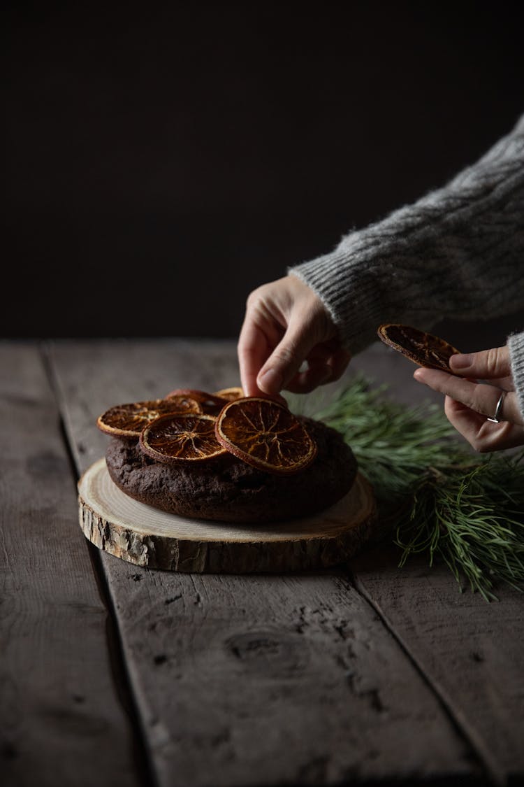 Woman Putting Dry Orange Slices On A Wooden Table