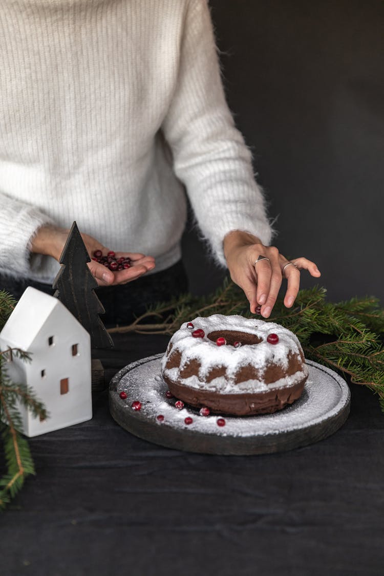 Person Putting Cranberries On A Cake