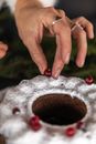 特写镜头中，一只手将蔓越莓放在撒了糖粉的平面上