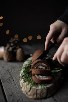 在带有节日装饰的木砧板上，巧克力圣诞原木被切片的特写镜头