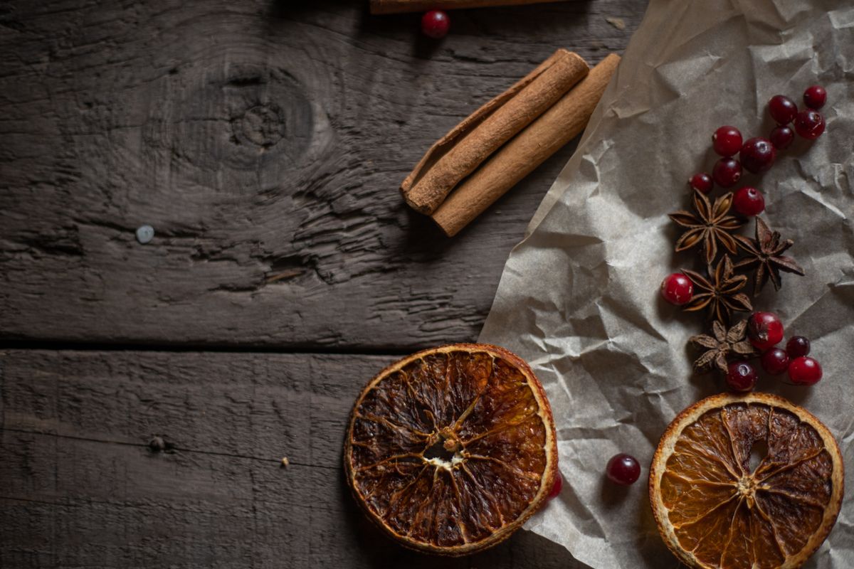 Dried orange slices, cinnamon, and cranberries arranged on wood