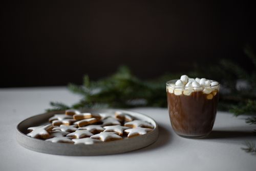 Free Plate of star-shaped cookies with frosting and hot cocoa topped with marshmallows, perfect for winter. Stock Photo