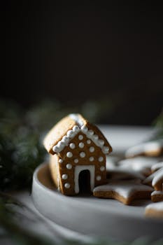 Close-up of a festive gingerbread house with star-shaped cookies on a plate, perfect for holiday celebrations.