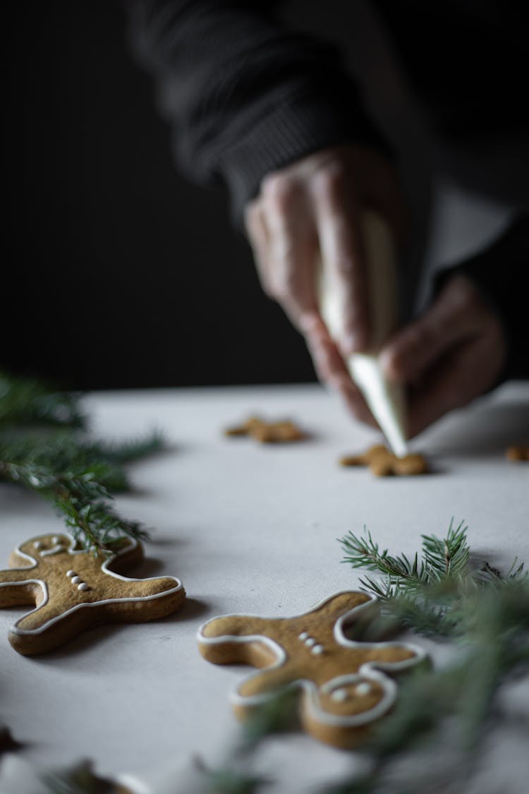 Person Holding A Piping Bag Frosting A Cookie