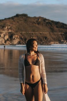 A woman in a bikini enjoys the ocean view at Arraial do Cabo beach.