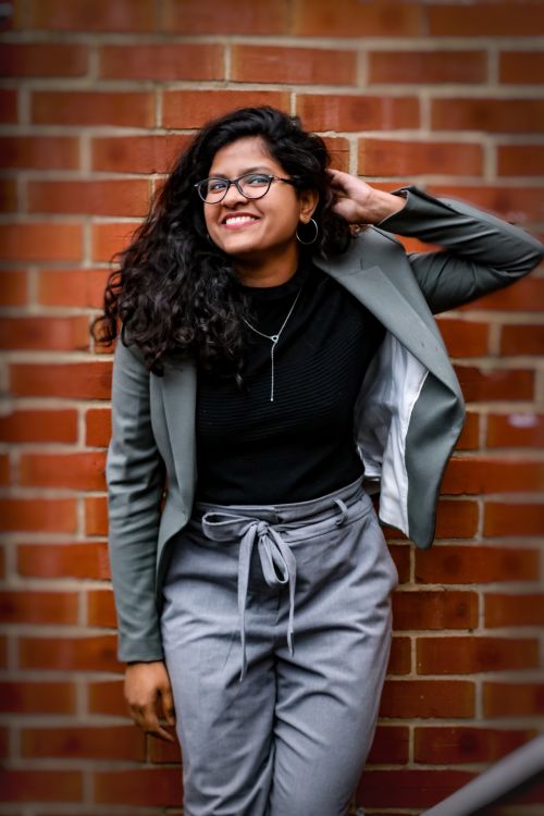 Free Cheerful woman in casual attire leaning on brick wall. Stock Photo