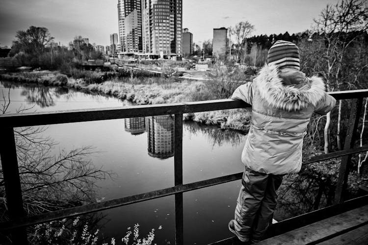 Grayscale Photography Of A Child On The Bridge Fence