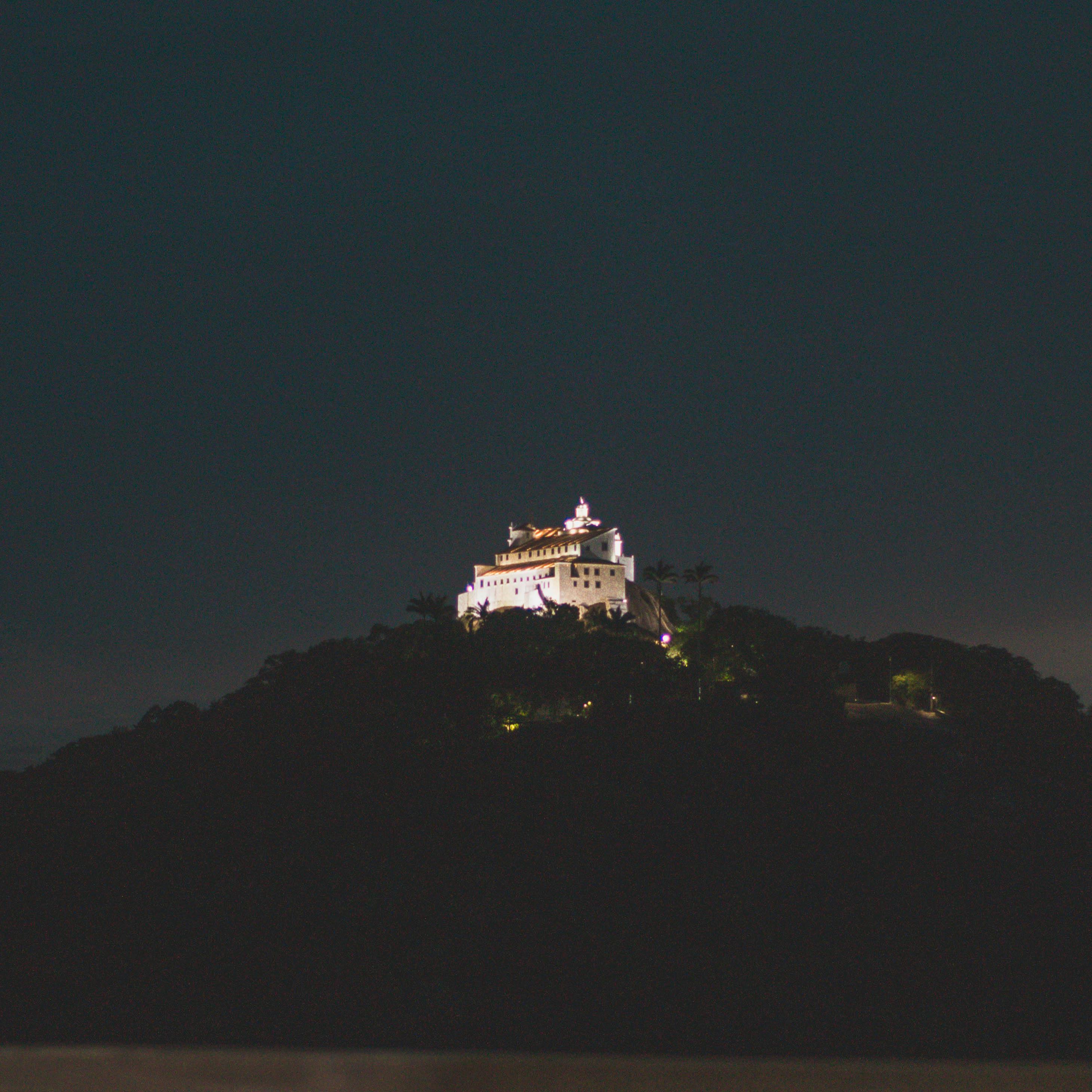 夜晚，山顶上矗立着一座美丽明亮的白色城堡，四周一片黑暗
