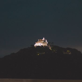 夜晚，山顶上矗立着一座美丽明亮的白色城堡，四周一片黑暗