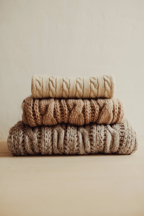 Stack of knitted sweaters on white surface