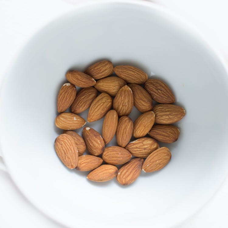 Nueces De Almendra Marrón En Cuenco De Cerámica Blanca