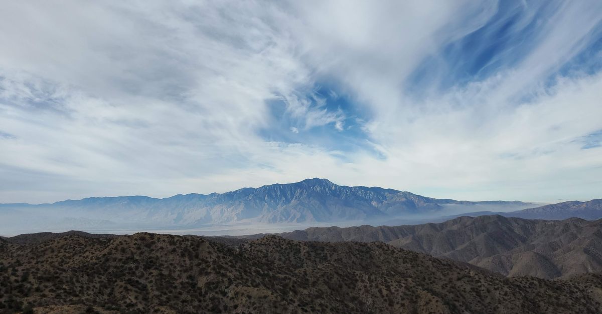 A breathtaking aerial view of Palm Desert's expansive mountains under a dramatic cloudy sky.