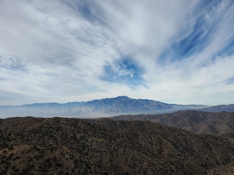 A breathtaking aerial view of Palm Desert's expansive mountains under a dramatic cloudy sky.