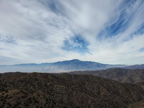 Free A breathtaking aerial view of Palm Desert's expansive mountains under a dramatic cloudy sky. Stock Photo