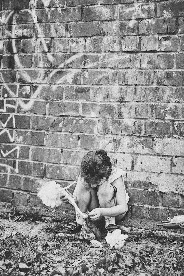 Girl Sitting On The Street Playing With A Doll